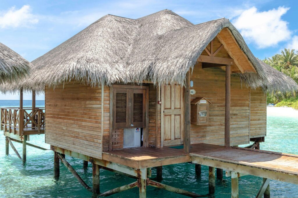 A scenic overwater bungalow with a thatched roof on a tropical Maldives island.